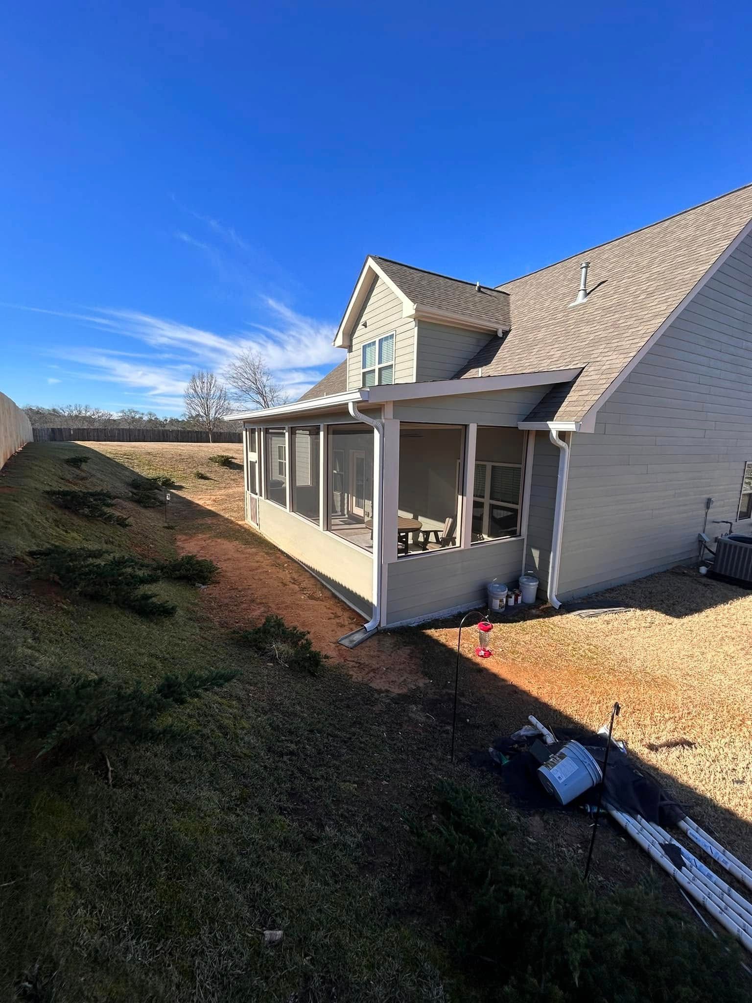 White house with covered porch and gravel yard under a clear blue sky