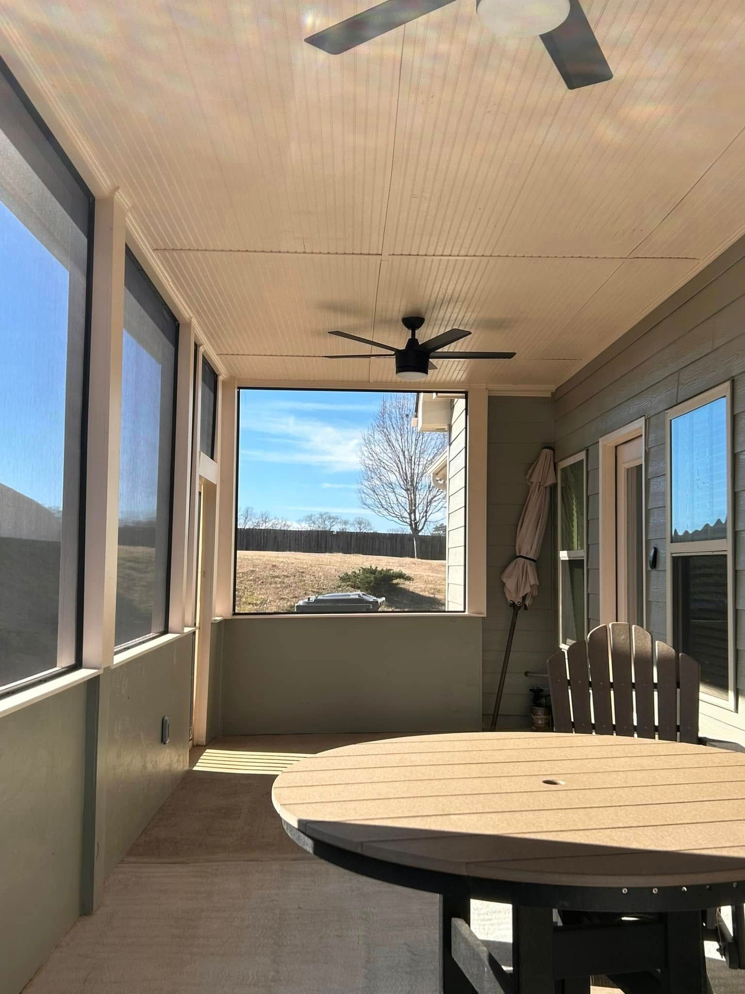 Covered patio with a round table, ceiling fan, and views of a desert landscape beyond the railing