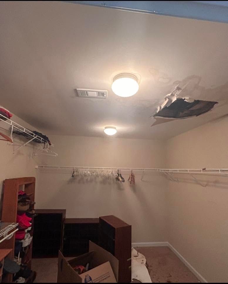 Bedroom closet with collapsed ceiling and a large hole above the light fixture