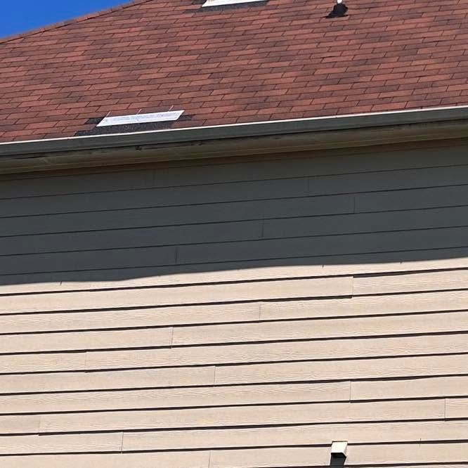 House exterior with beige siding and a red shingled roof, showing two skylights.