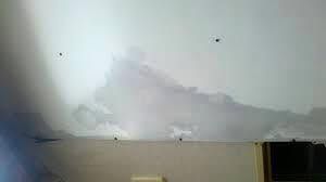 Peeling white ceiling above a wall and doorway, with water damage or mold discoloration