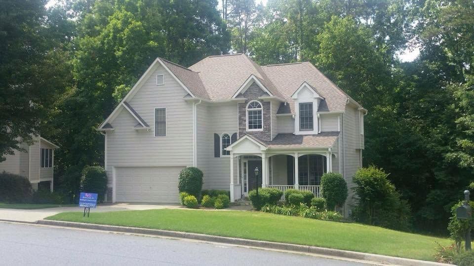 Suburban beige house with manicured lawn and trees on a quiet street