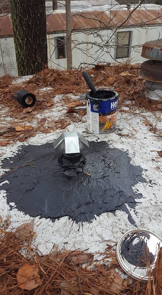 Snowy yard with a wet black patch, a small white object, and a bucket near a tree.
