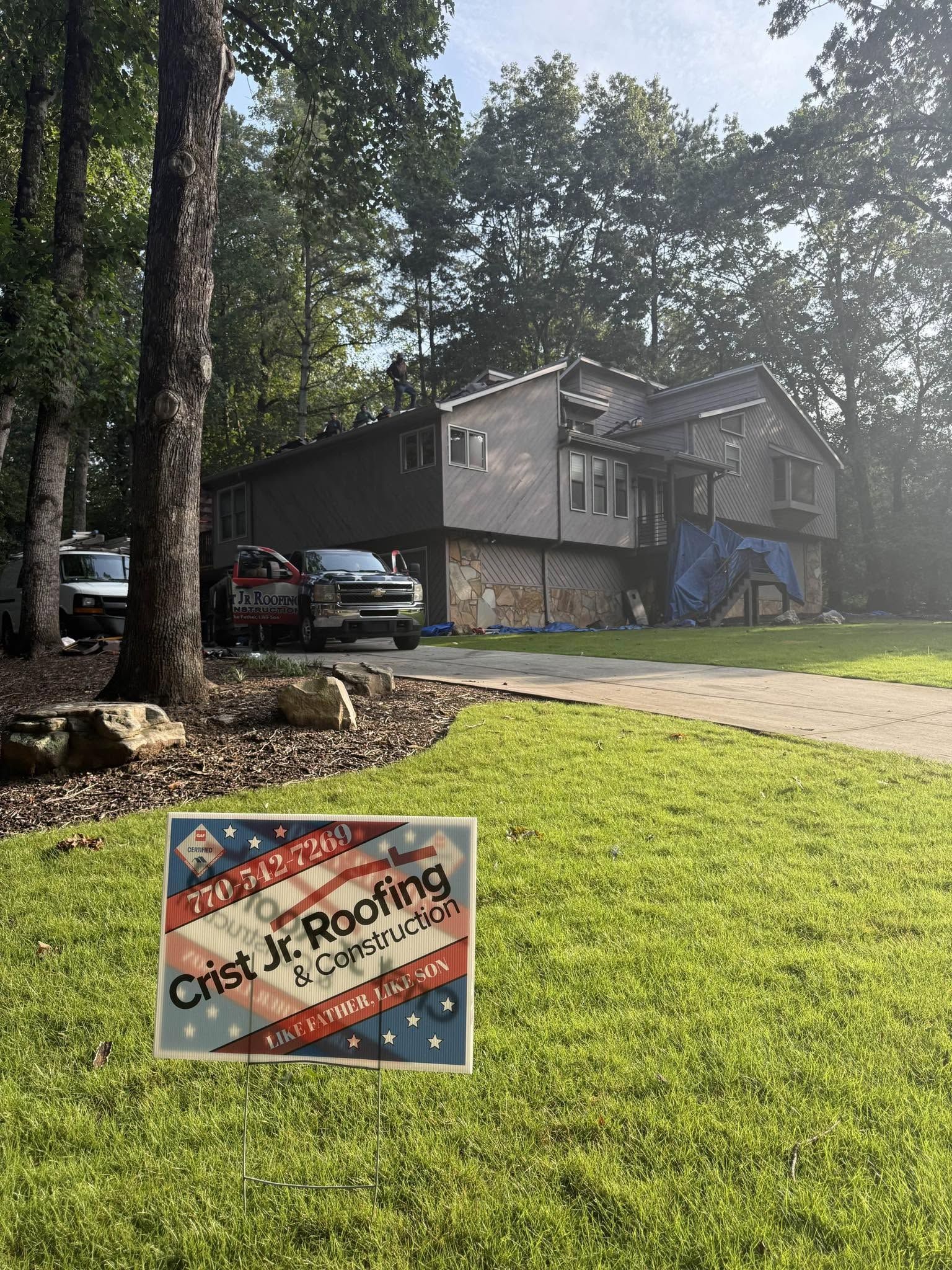 Suburban house with a driveway; lawn sign reads “Crisp Roofing” in the foreground.
