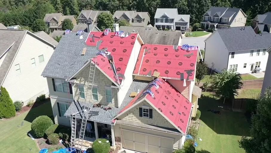 Aerial view of a house with a partially replaced red roof in a suburban neighborhood.