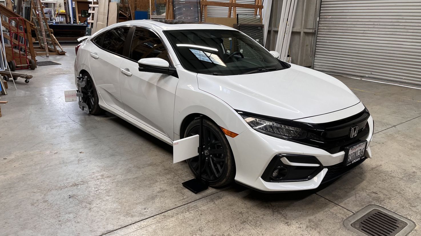 A white honda civic is parked in a garage.