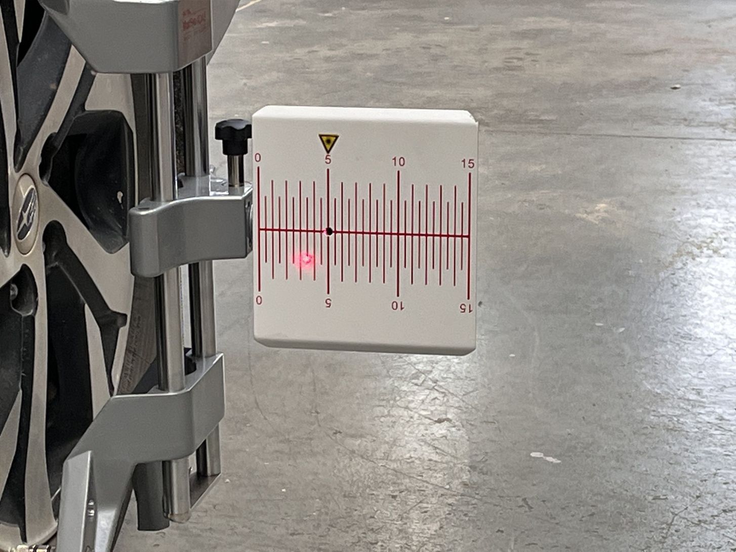 A measuring device is attached to the side of a car wheel.