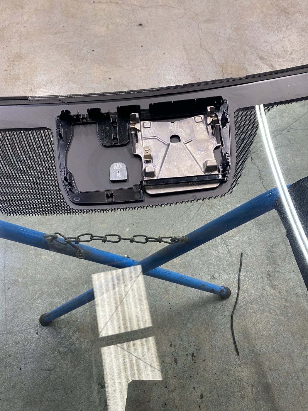 A car windshield is sitting on top of a blue stand.