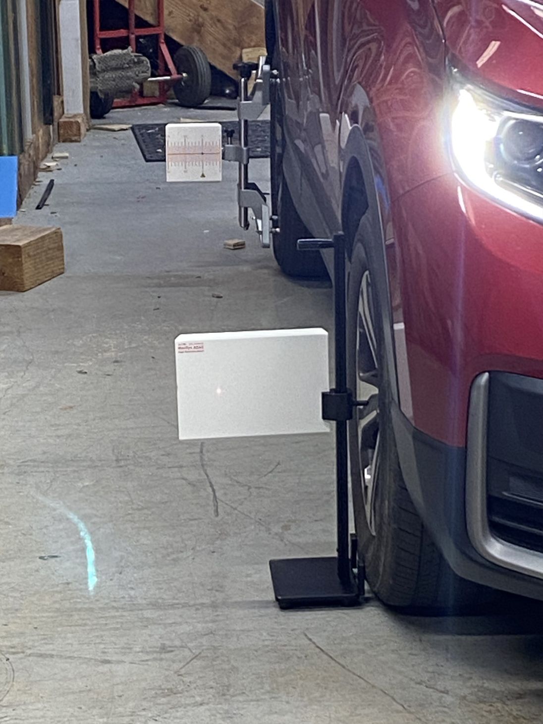A red car is being adjusted in a garage.