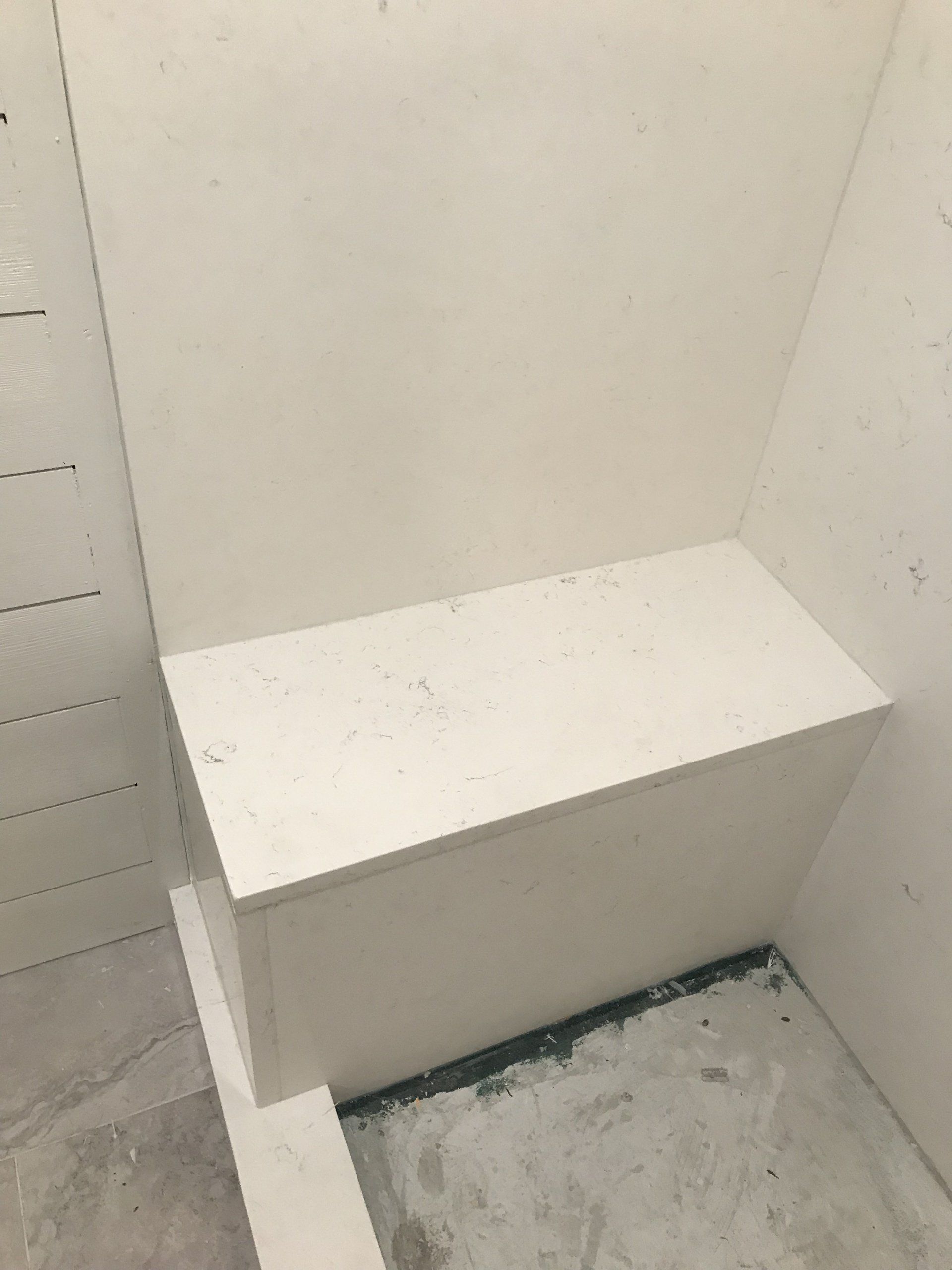 A white bench is sitting in a room next to a wall.