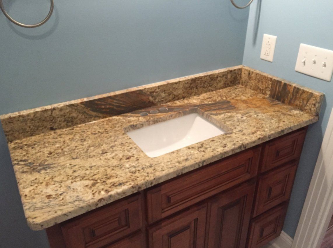 A bathroom vanity with a granite counter top and a sink