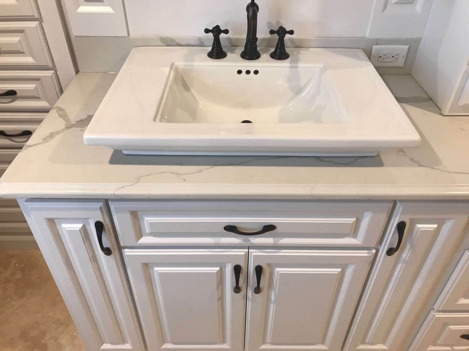 A bathroom vanity with a white sink and black faucet