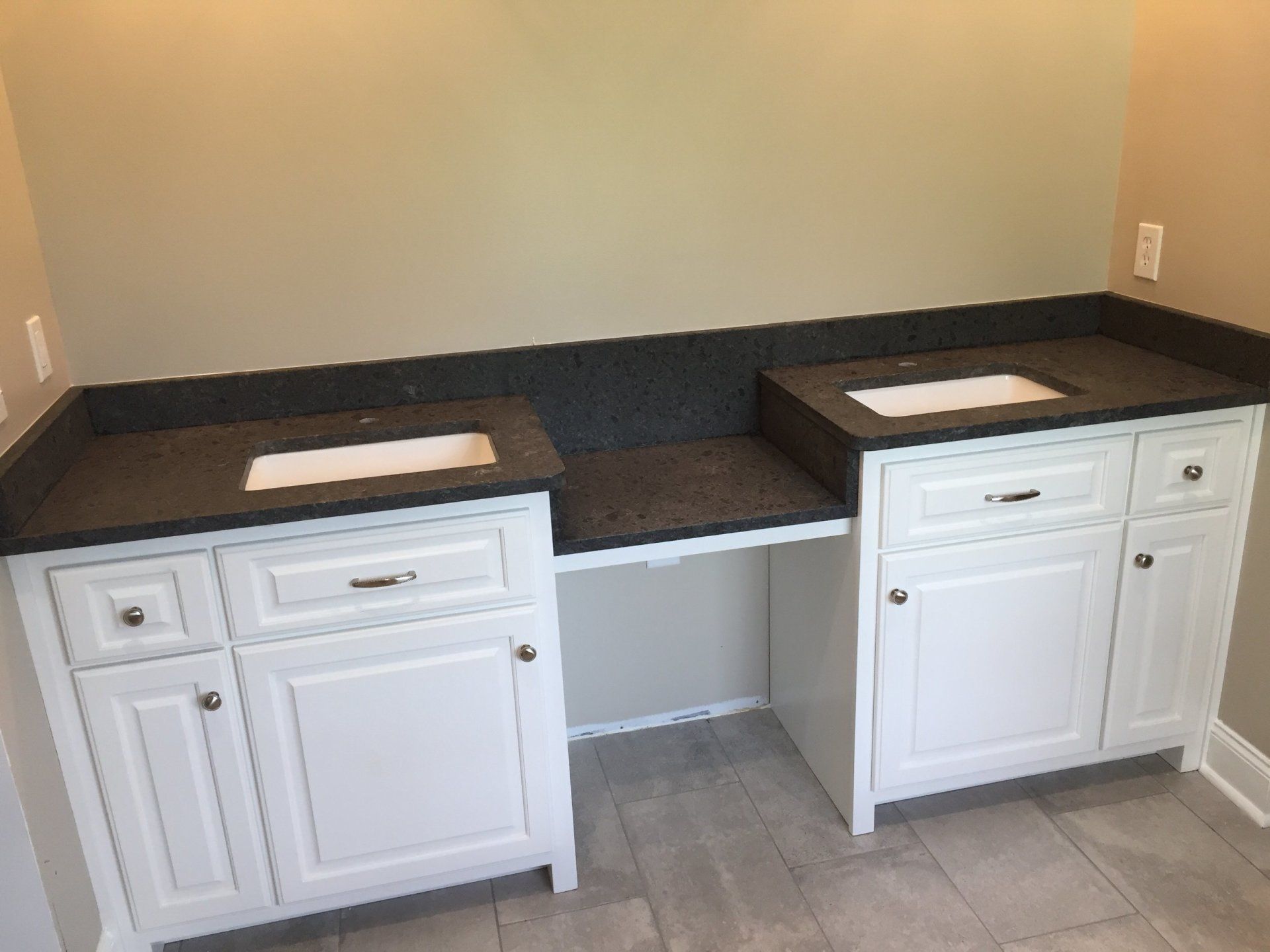 A bathroom with two sinks and white cabinets.