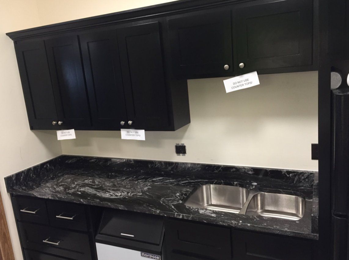 A kitchen with black cabinets and granite counter tops