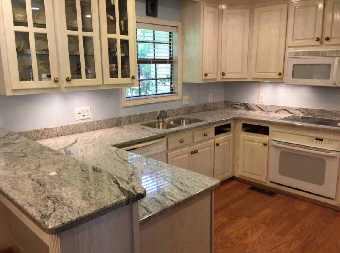 A kitchen with white cabinets and granite counter tops.