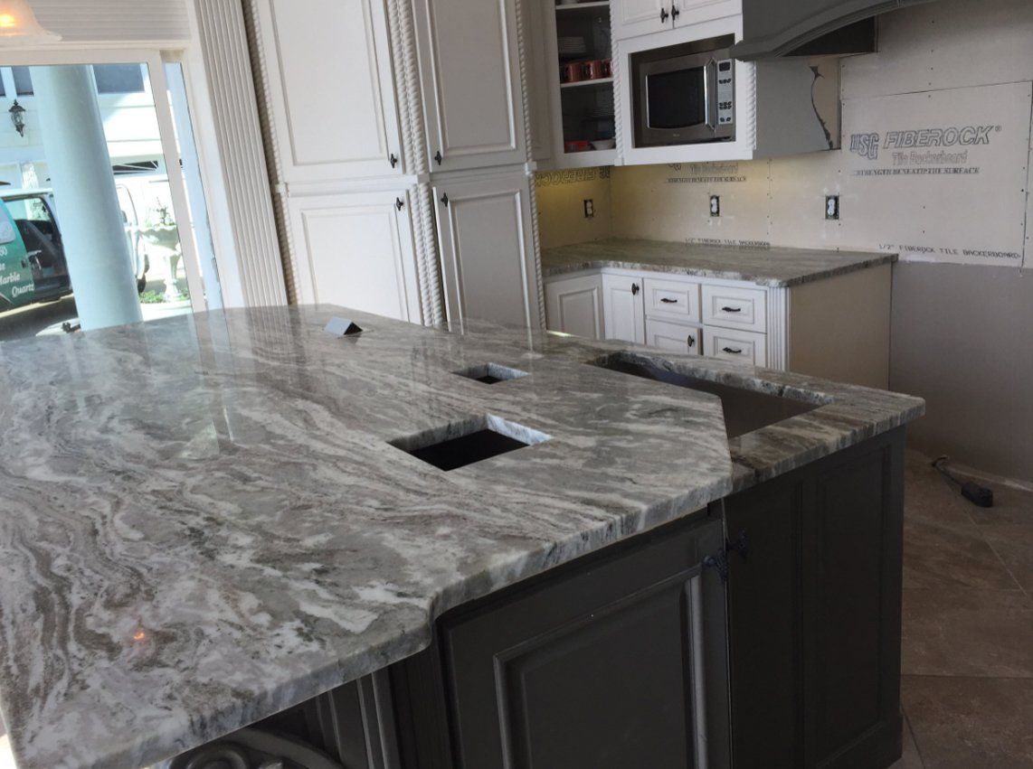 A kitchen with granite counter tops and white cabinets.
