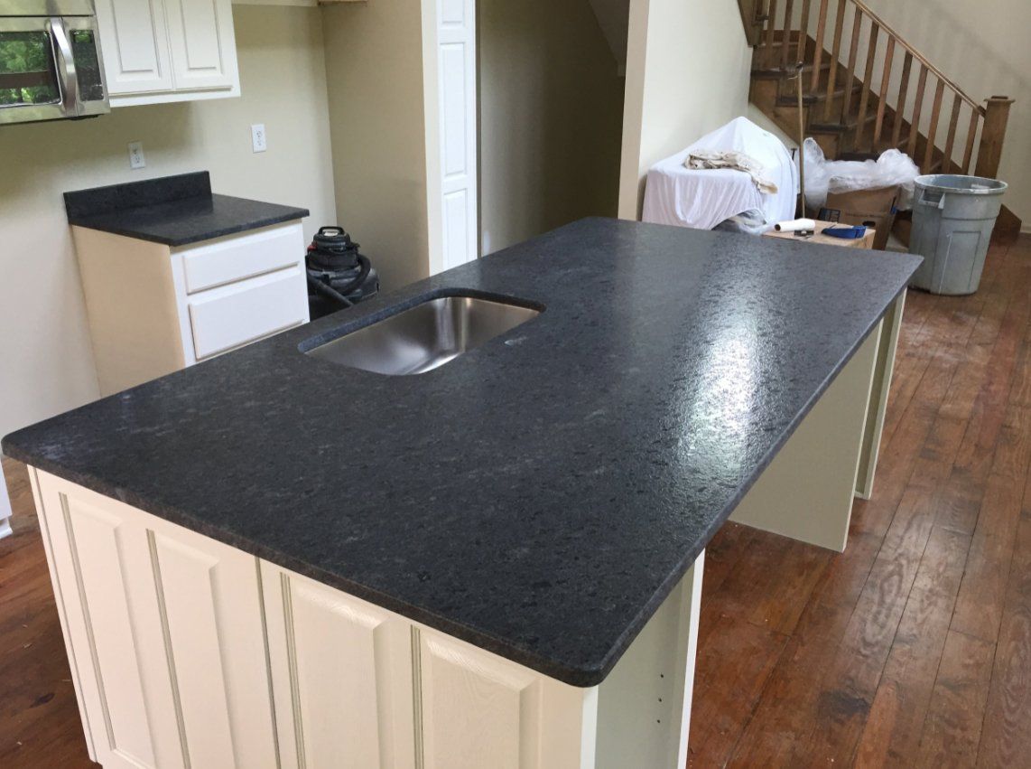 A kitchen with a black granite counter top and a sink.