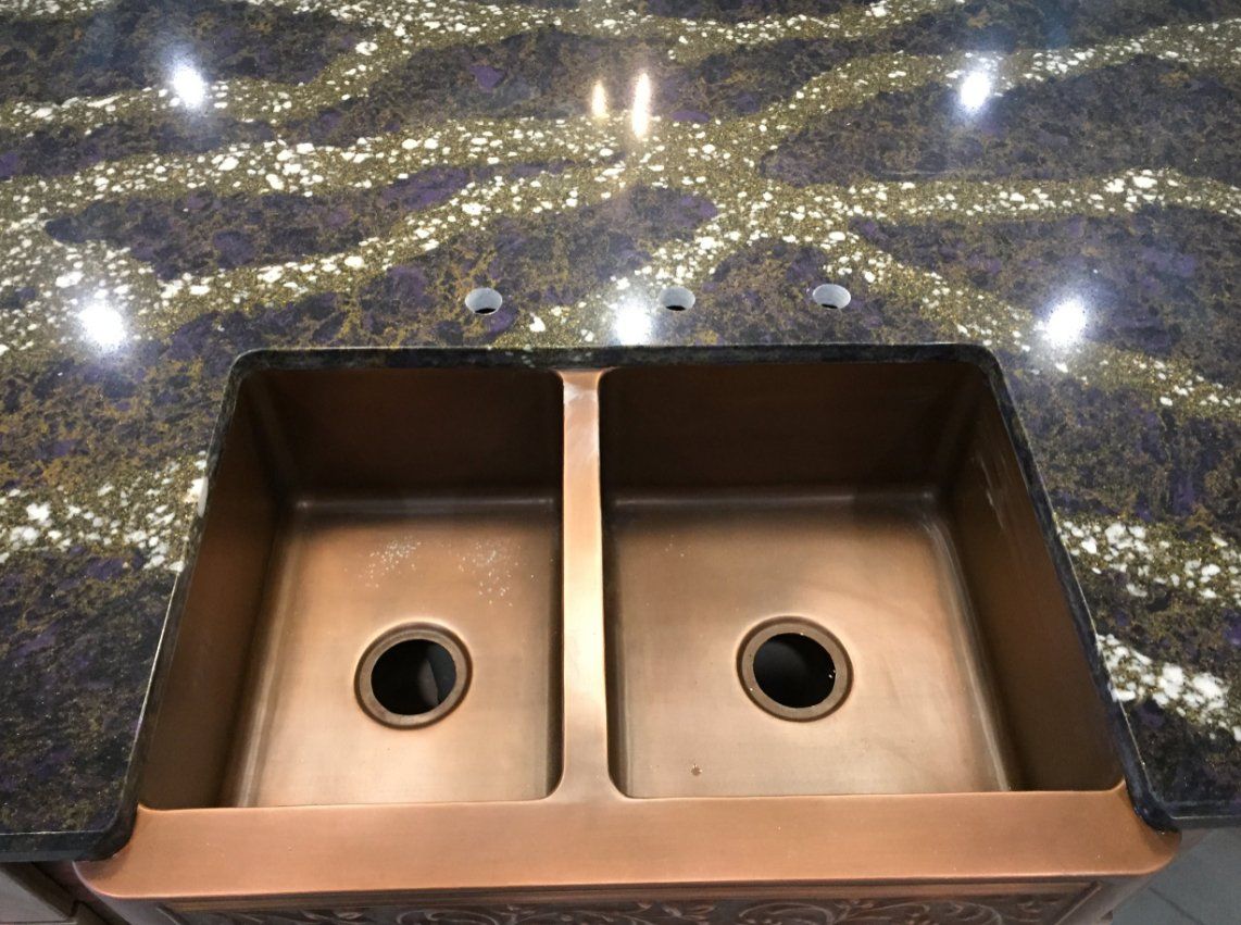 A kitchen sink is sitting on top of a granite counter top.