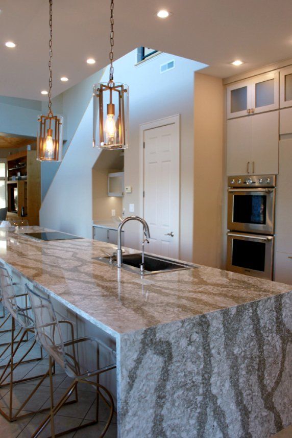 A kitchen with a large island , sink , and stainless steel appliances.