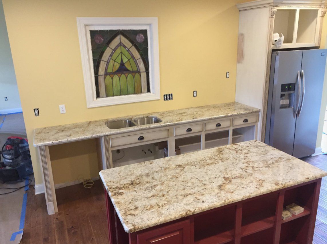 A kitchen with granite counter tops , a sink , and a refrigerator.