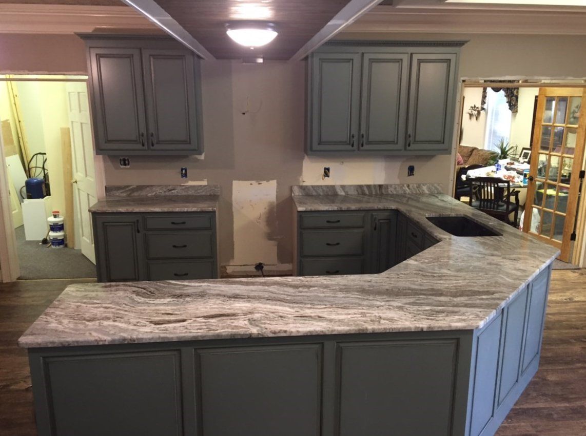 A kitchen with gray cabinets and a granite counter top.