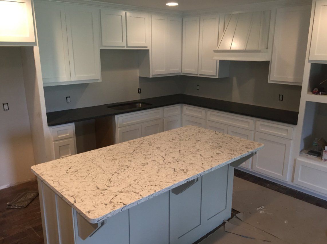 A kitchen with white cabinets and a large island in the middle.