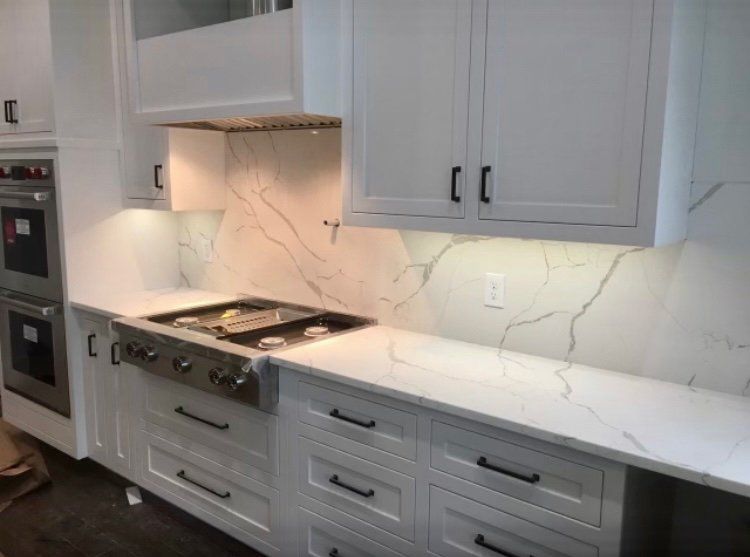 A kitchen with white cabinets and a stove top oven.
