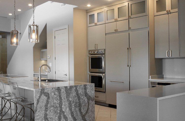 A kitchen with white cabinets , granite counter tops , stainless steel appliances and a large island.