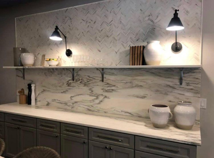 A kitchen with a marble wall and a shelf with vases on it.