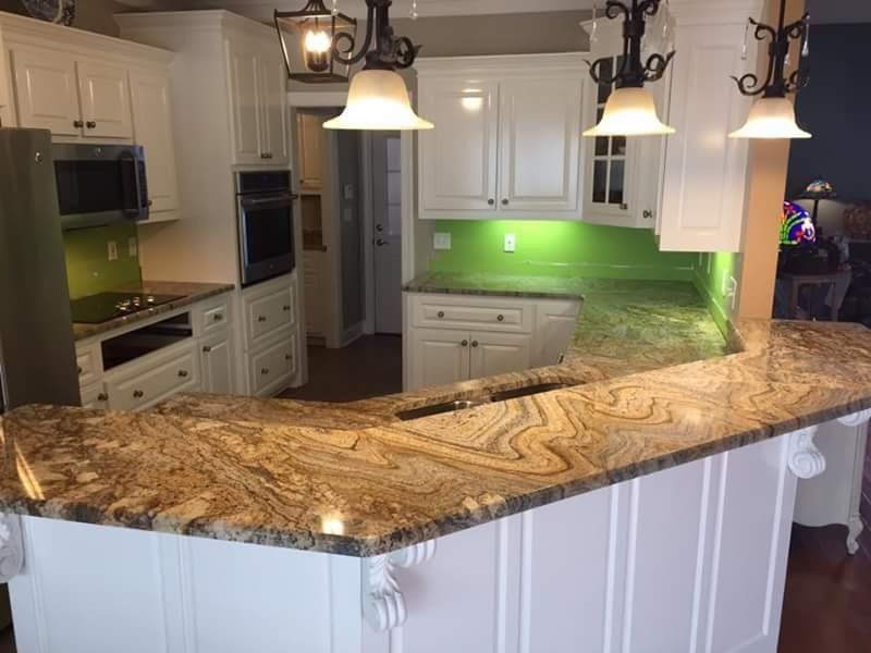A kitchen with white cabinets and granite counter tops.