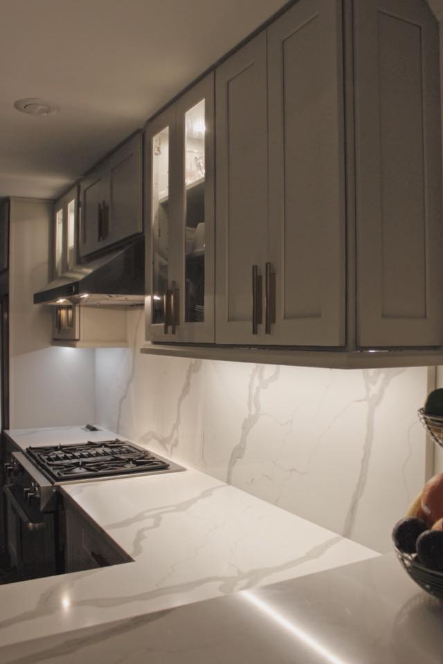 A kitchen with gray cabinets and white counter tops