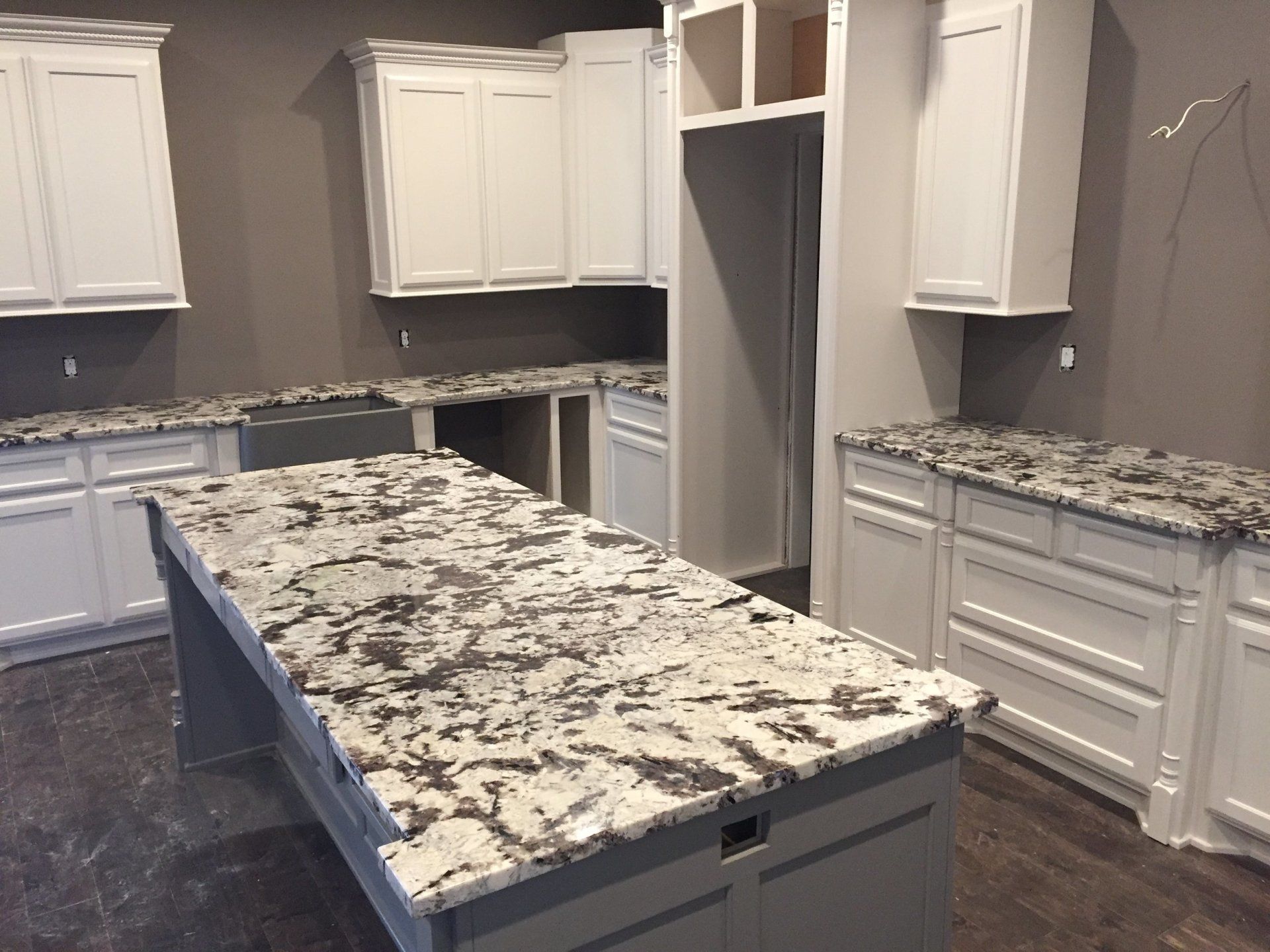 A kitchen with granite counter tops and white cabinets