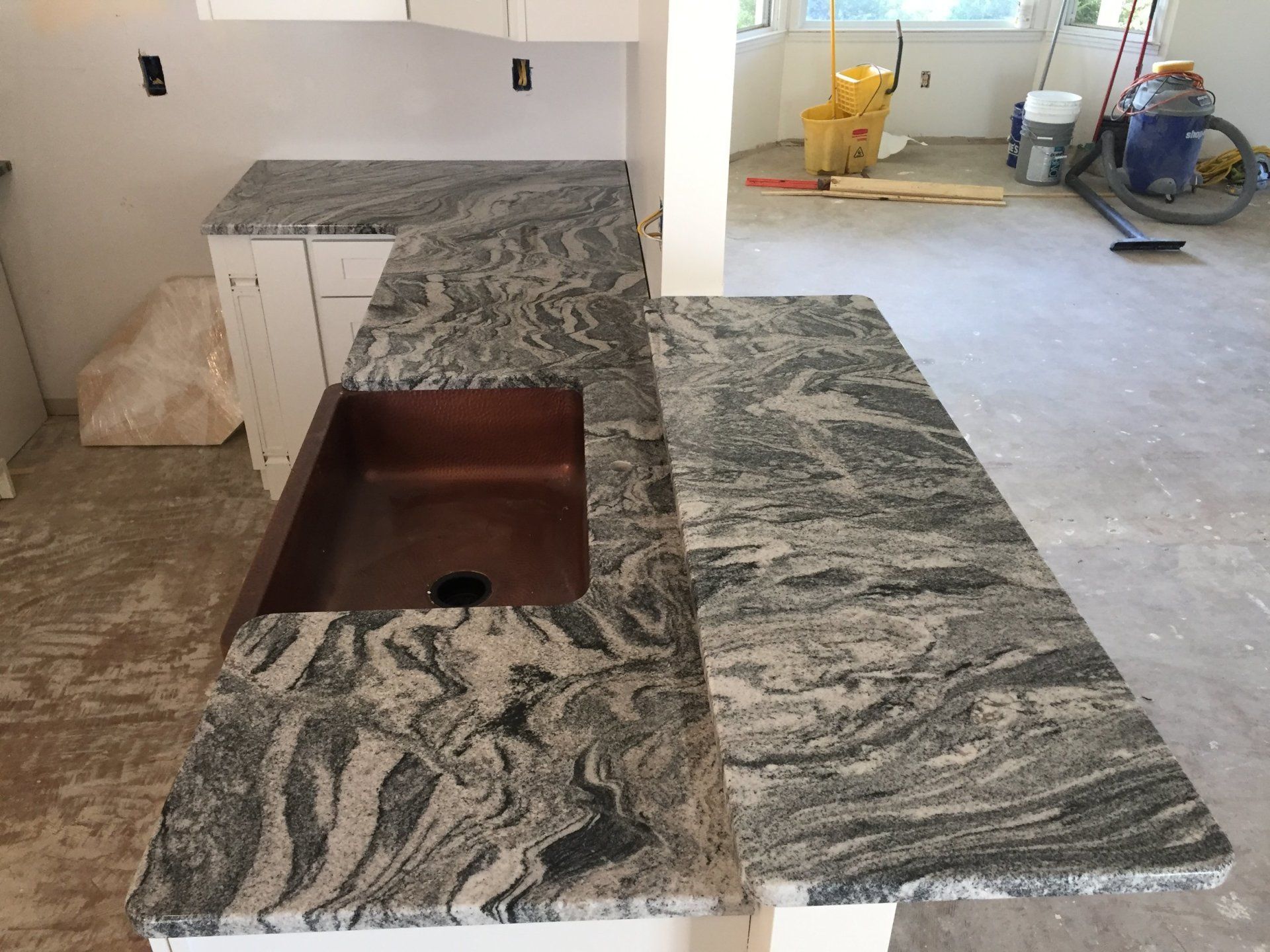 A kitchen with granite counter tops and a copper sink