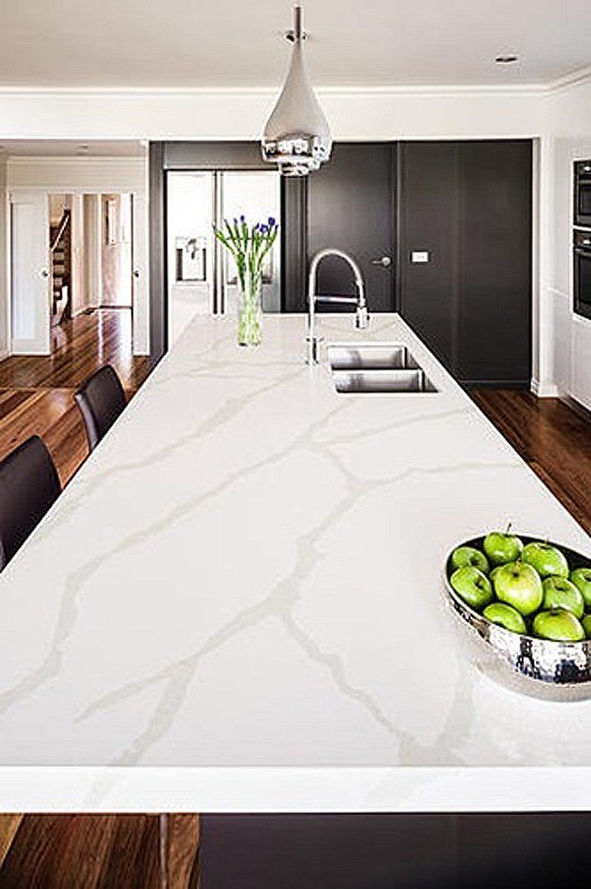 There is a bowl of apples on the counter in the kitchen.