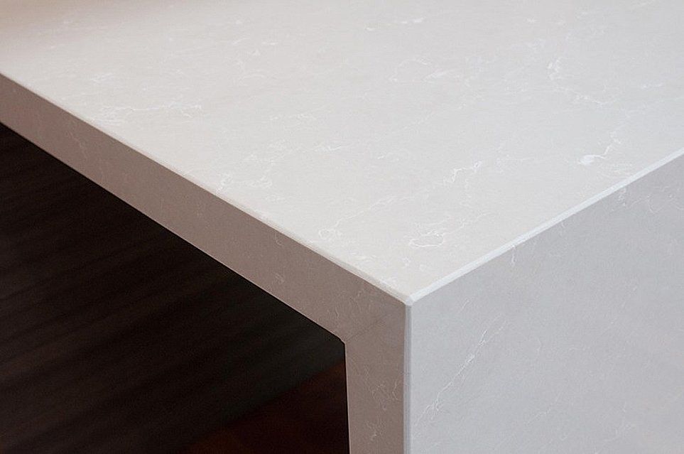 A close up of a white counter top on a wooden floor.
