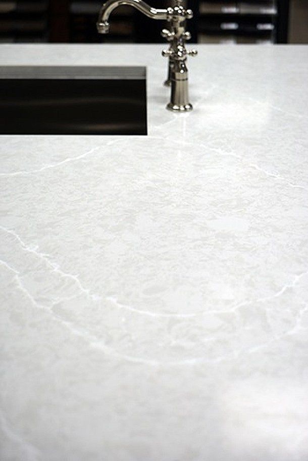 A faucet is sitting on a white counter next to a sink.
