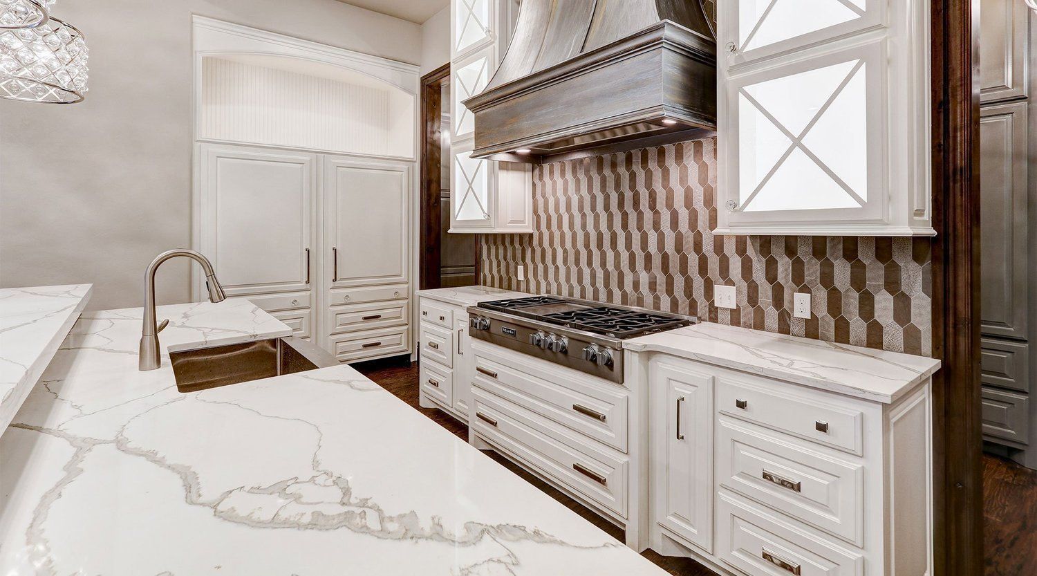 A kitchen with white cabinets , stainless steel appliances , and a large island.