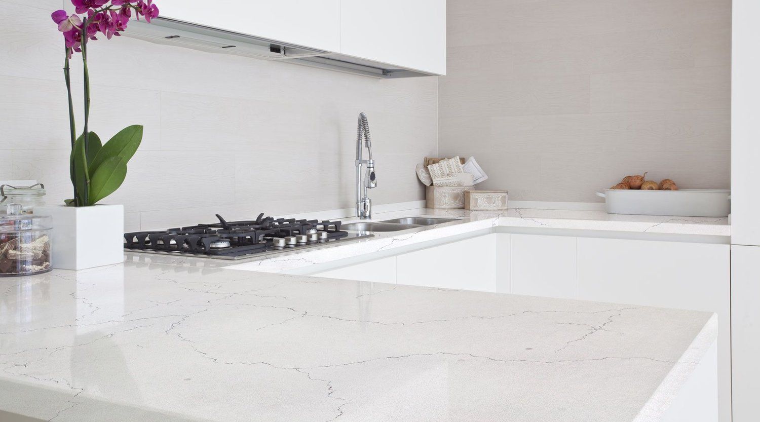 A kitchen with white cabinets , a stove top oven , a sink , and a counter top.
