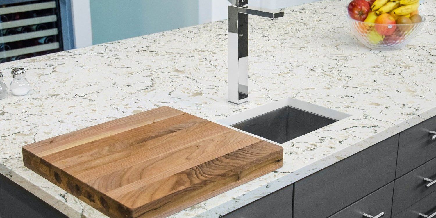 A wooden cutting board is sitting on top of a kitchen counter next to a sink.
