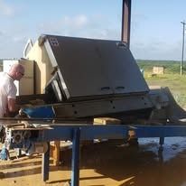 Man operating large industrial machinery outdoors near a field.