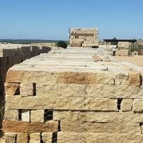 Stacked rectangular sandstone blocks outdoors under a clear blue sky.