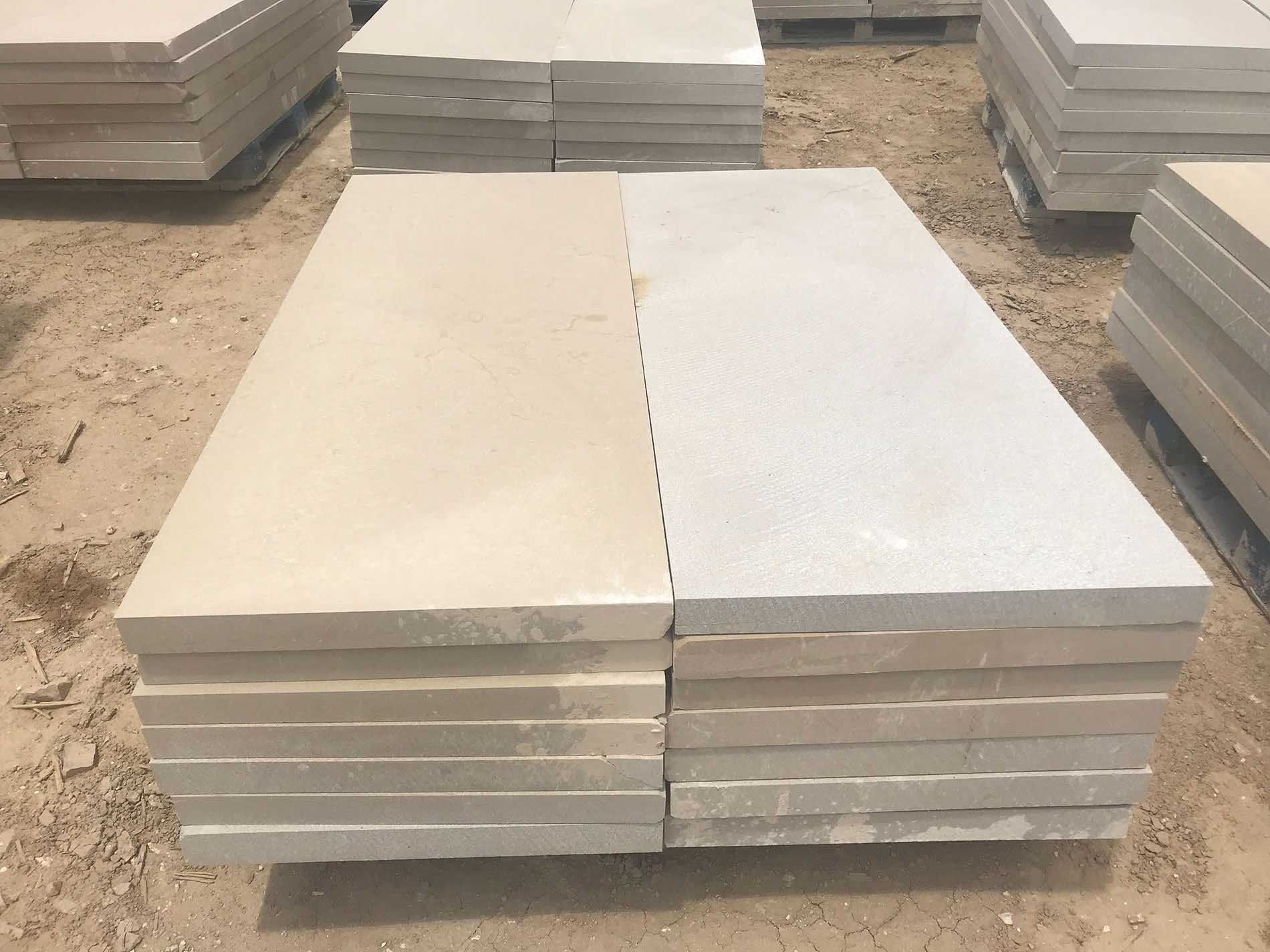 Stacks of light beige and cream-colored rectangular stone pavers.