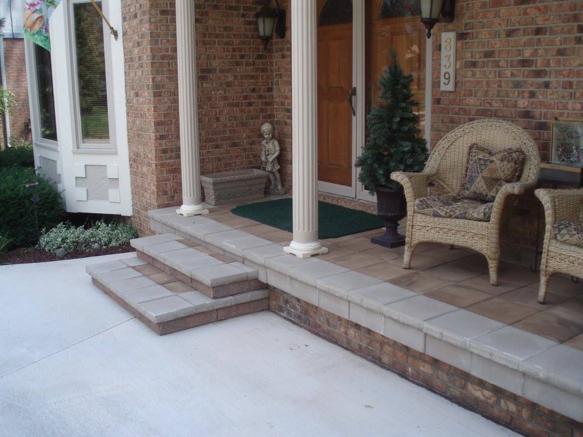 Brick home front porch with steps, columns, and wicker furniture.
