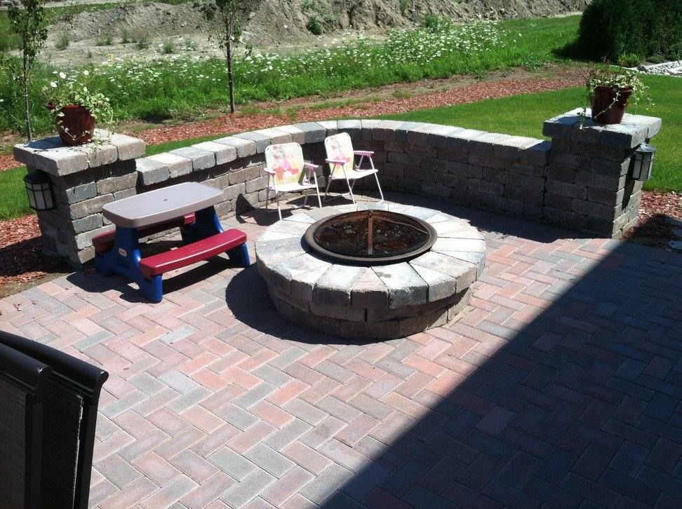 Brick patio with built-in fire pit, low brick wall, and seating. Includes a small picnic table and two chairs.