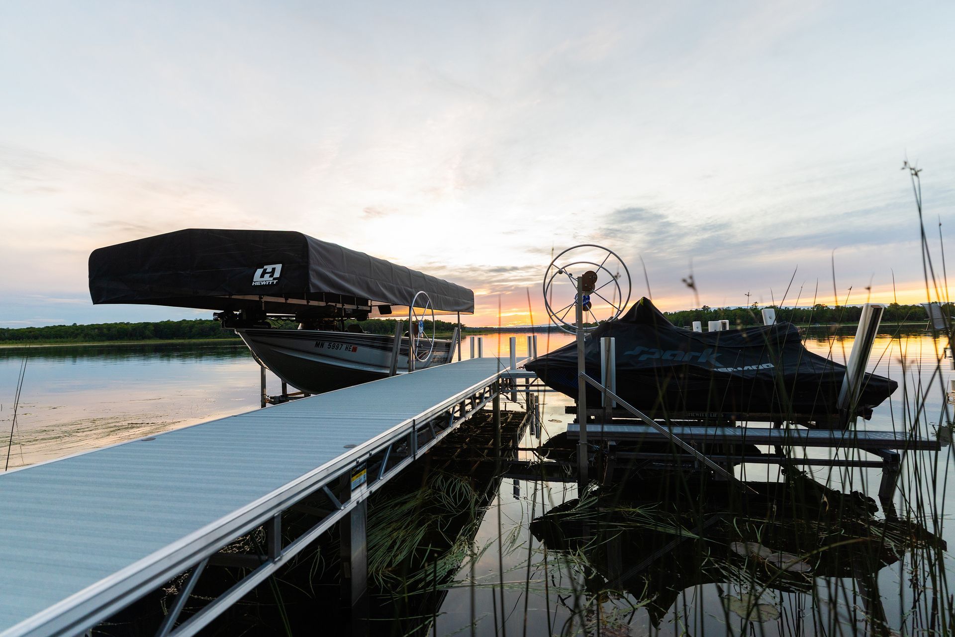 Sunset over a waterfront dock with a white walkway.