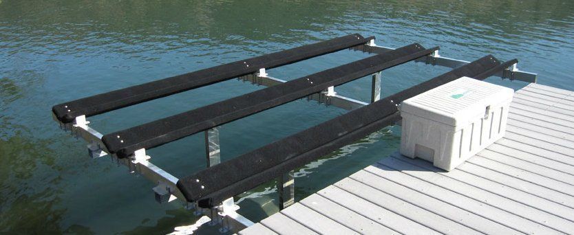 A boat lift platform extending over water attached to a dock with a storage box on the dock.