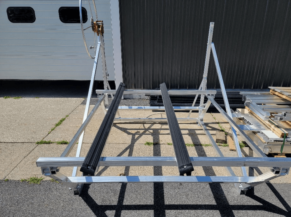 Aluminum boat rack with two black padded rails, outside, sunny.