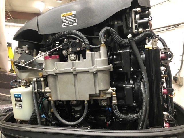 Close-up of a black boat engine with various components and tubing visible.