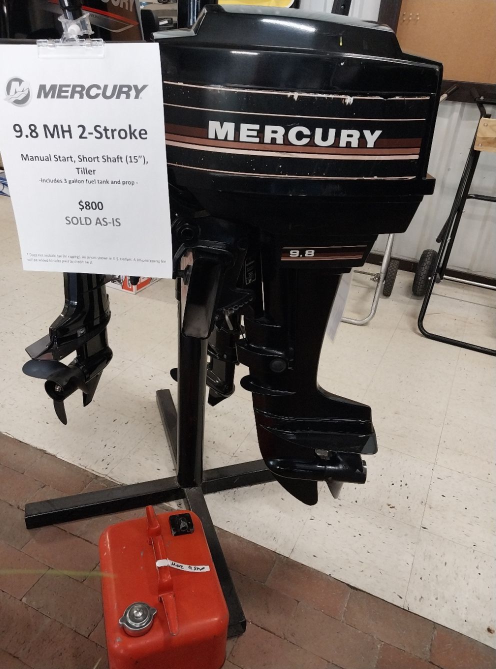 Black Mercury 9.8 MH 2-Stroke outboard motor on a black stand, with a red fuel tank.