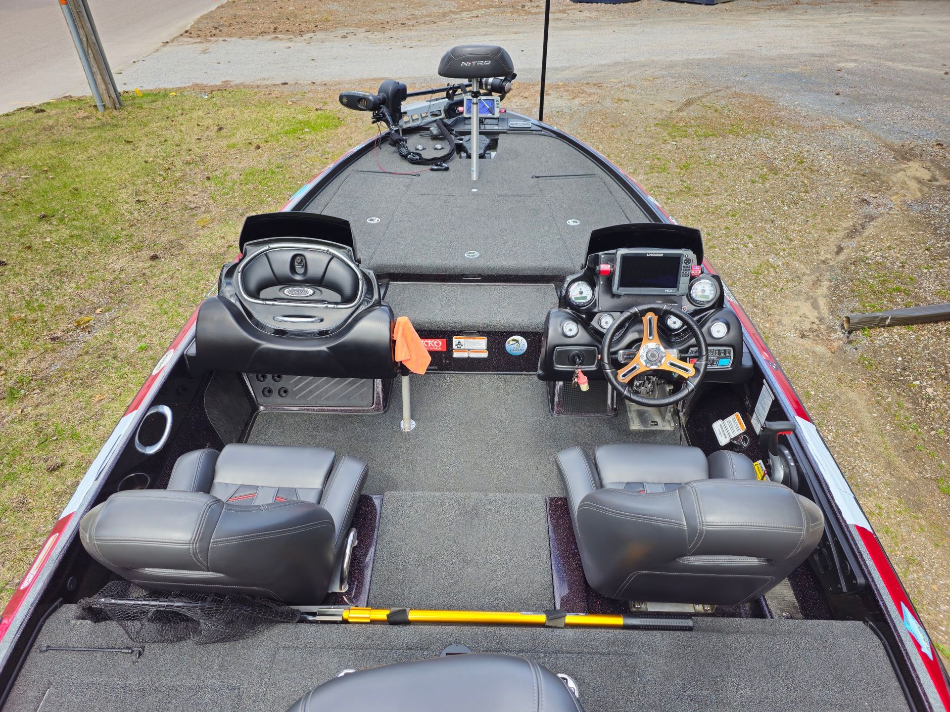 Bass boat interior with two seats, steering wheel, and navigation display on deck.